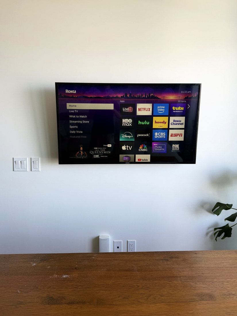 A TV mounted on a white wall with no visible cables, above a wood table