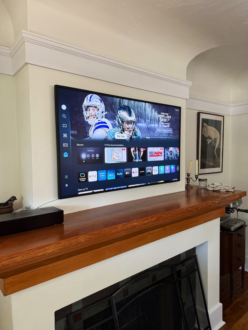 A TV mounted in the alcove above a wood craftsman fireplace mantel