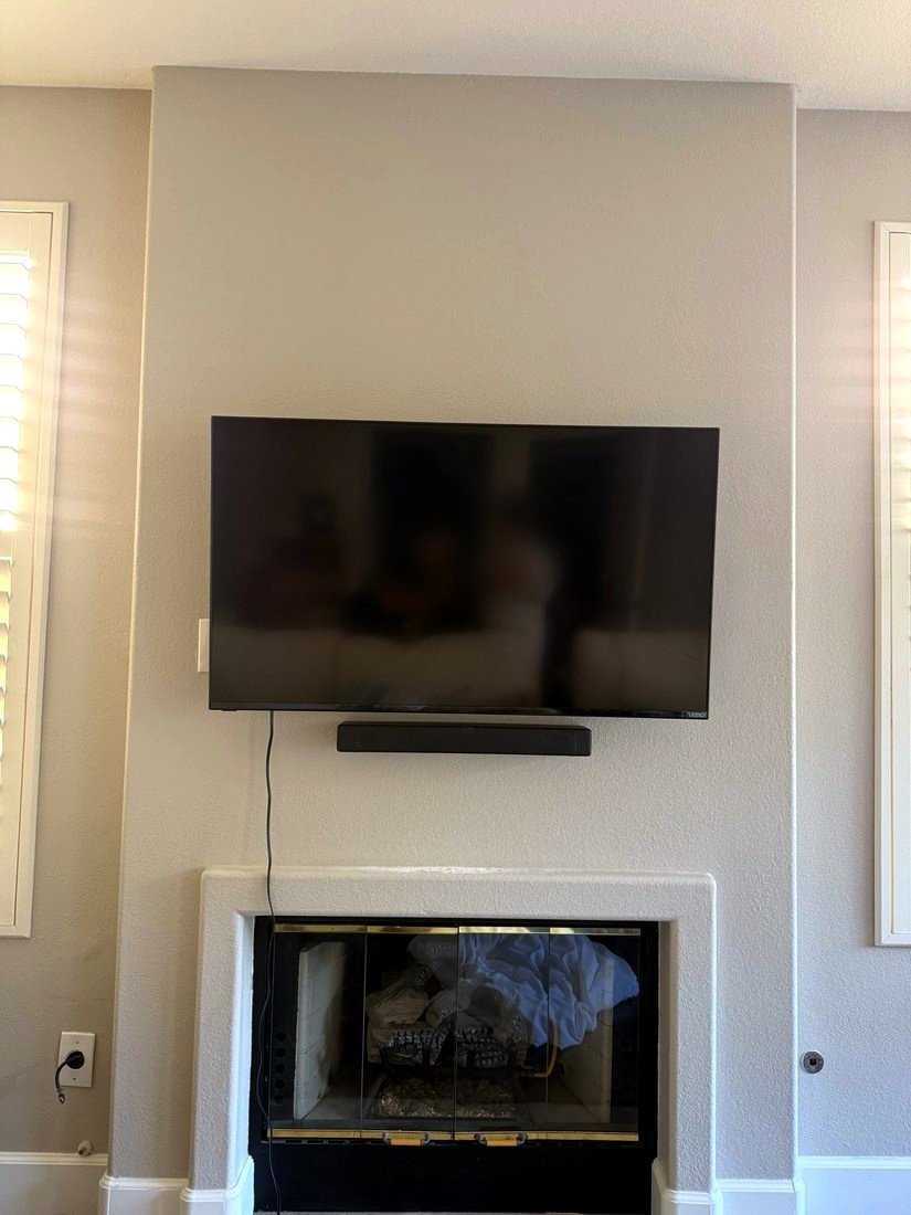 A TV with a soundbar mounted above a white fireplace