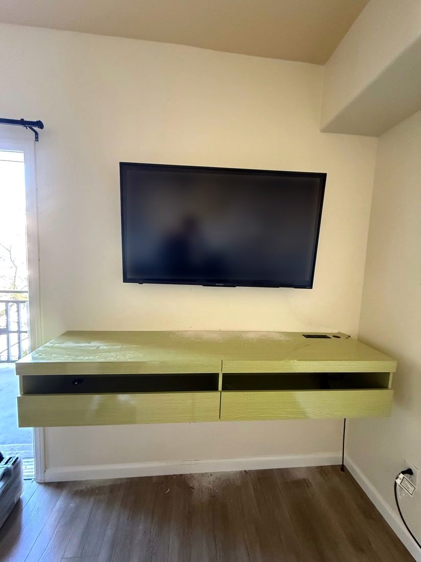 A TV mounted above a green floating console