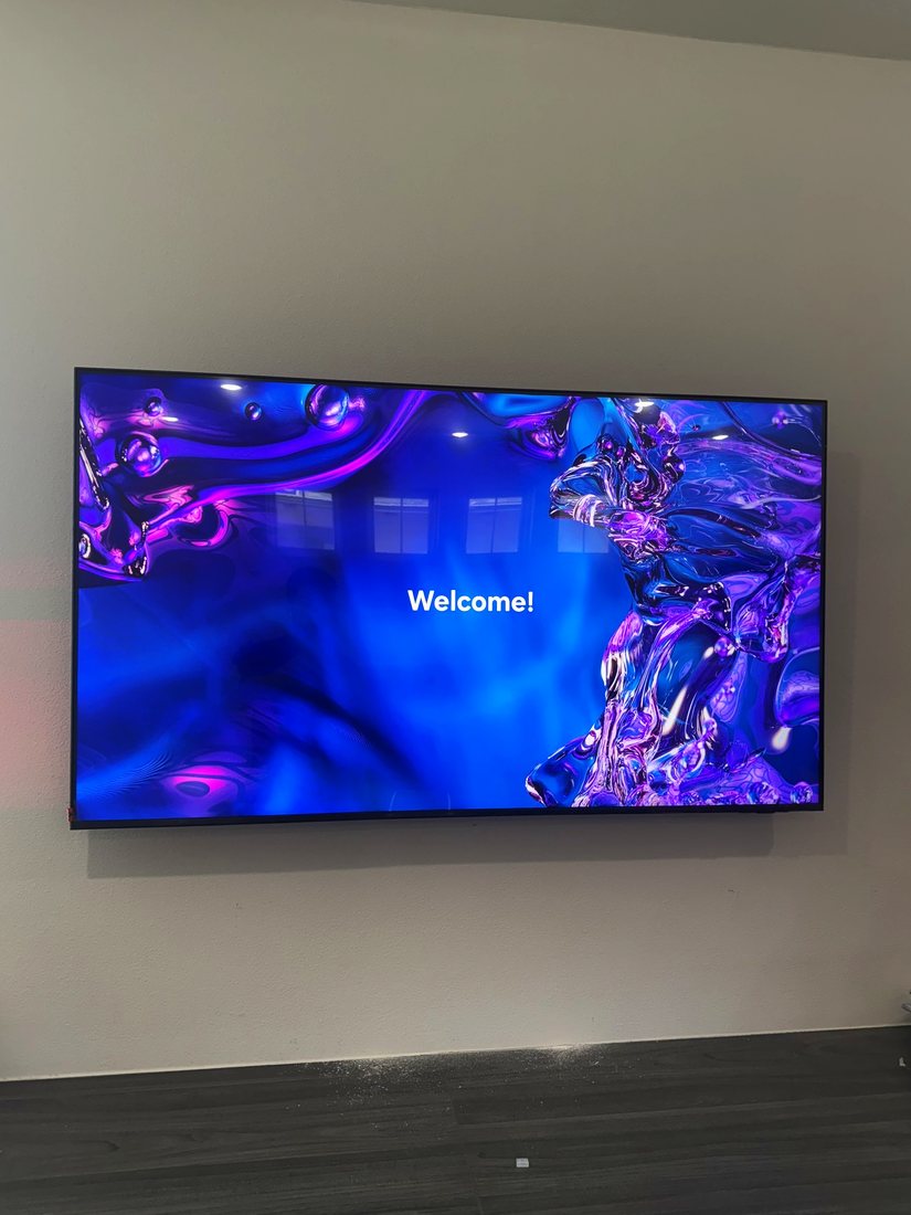 A large TV mounted on a gray wall with no visible cables