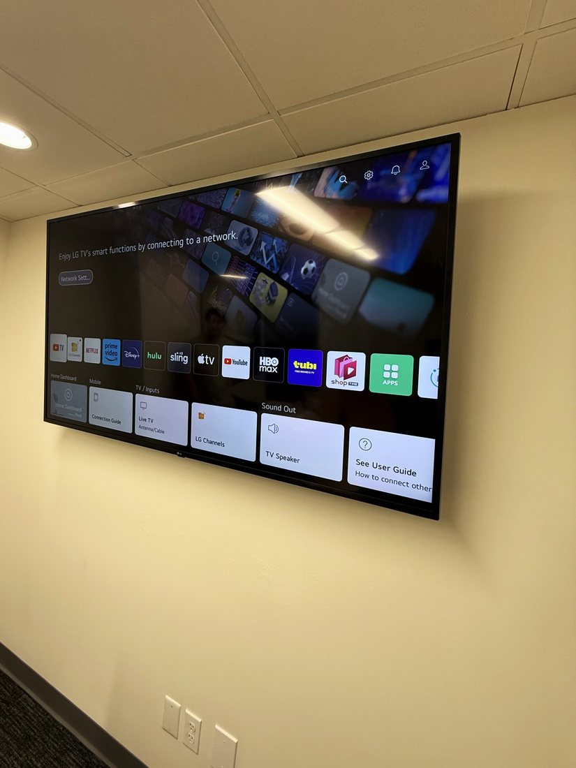 A large TV mounted on the wall of a small meeting room