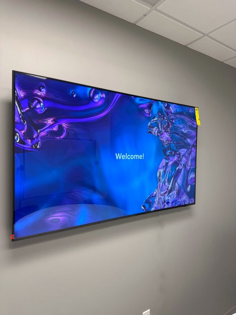A large display mounted on an office wall showing a welcome screen