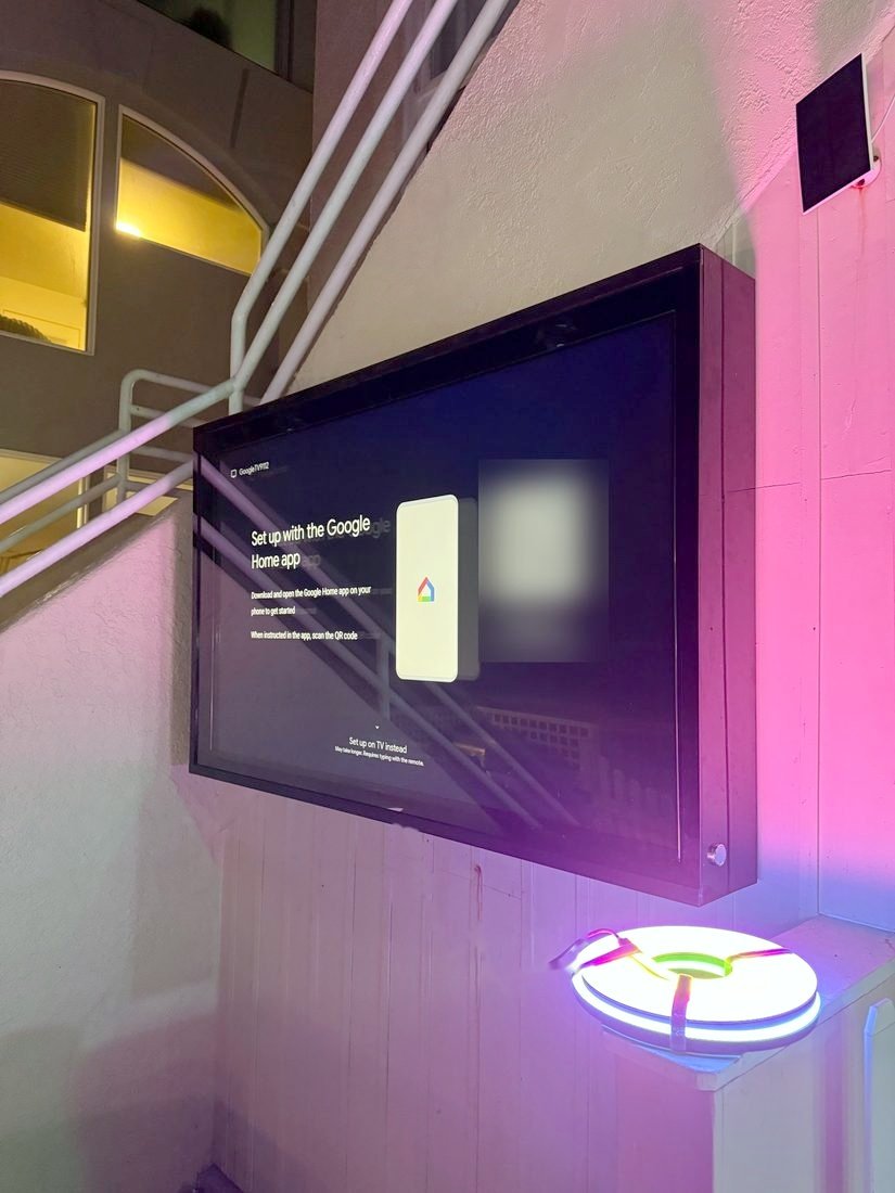 A TV in a protective enclosure mounted on an outdoor wall at night