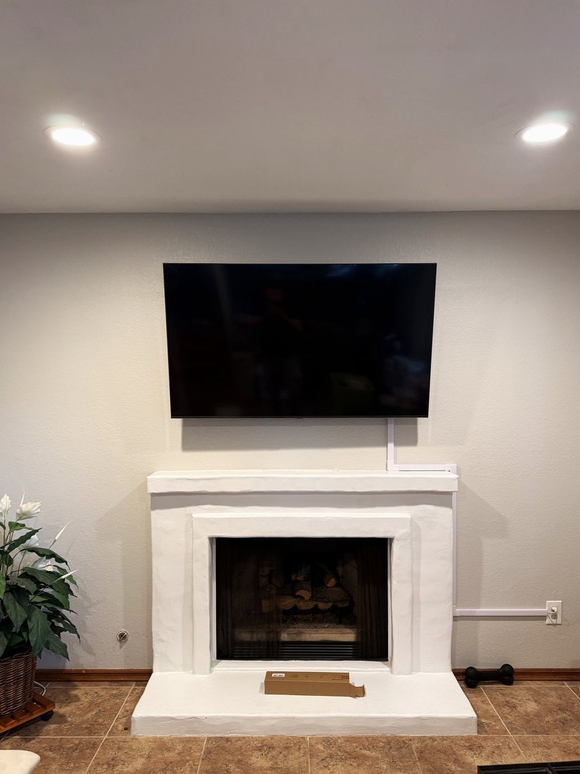 A TV mounted on a gray wall above a white plaster fireplace