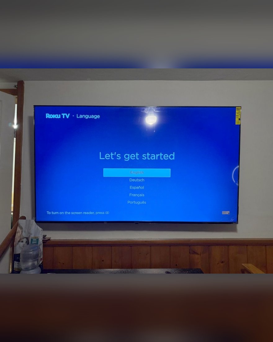 A wall-mounted TV showing its first setup screen