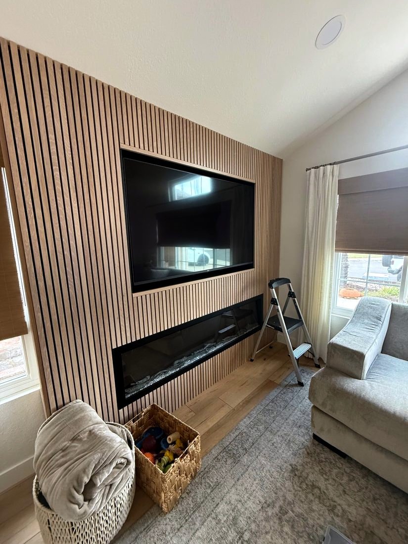 A TV recessed into a wood slat wall above a linear fireplace