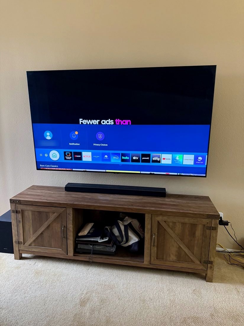 A large TV mounted above a wooden console with a soundbar