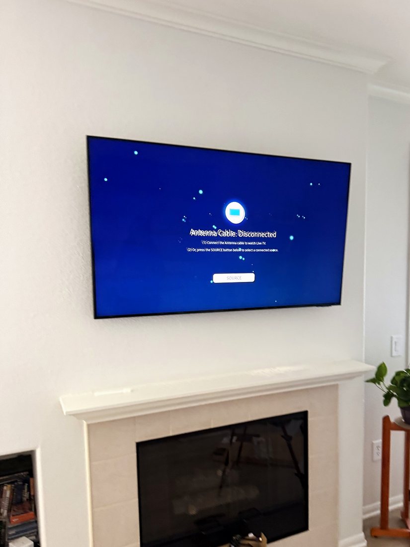 A TV mounted above a white tiled fireplace in a bright living room