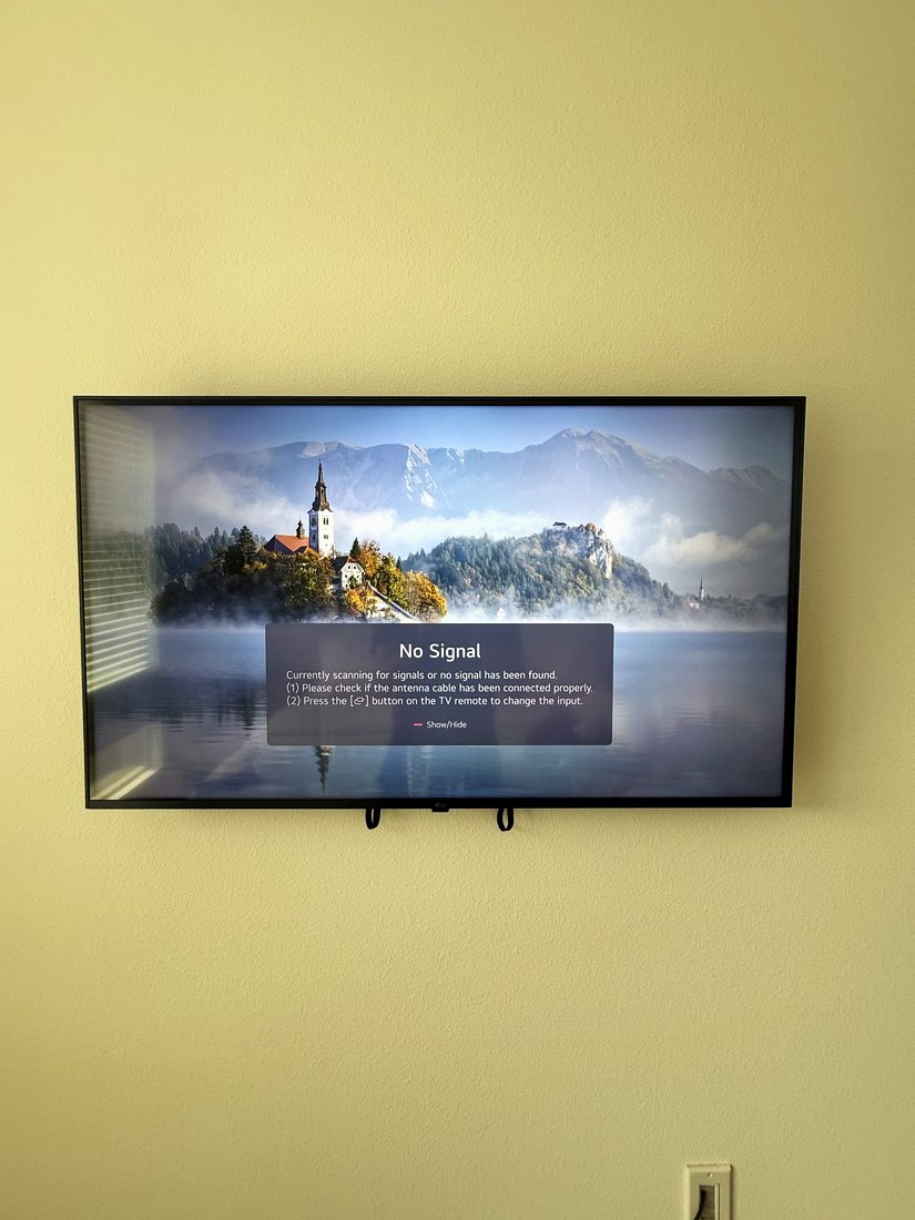 A TV mounted on a yellow wall with no visible cables